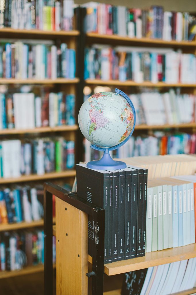 A globe and book stack in a library, symbolizing education and global knowledge.